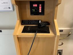 View of the podium. The podium has display cables, and a control panel to manage inputs. The podium is not height adjustable, but the podium is accessible for instructors.