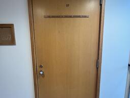 The entryway of room 207 in Watson Hall is a wooden door with a doorknob on the left side.