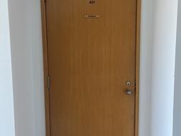The entryway of room 401 in Watson Hall is a wooden door with a doorknob on the right side.