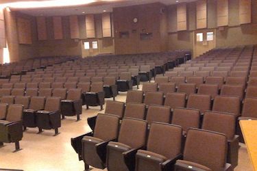 Large auditorium with brown seats and beige colored walls.