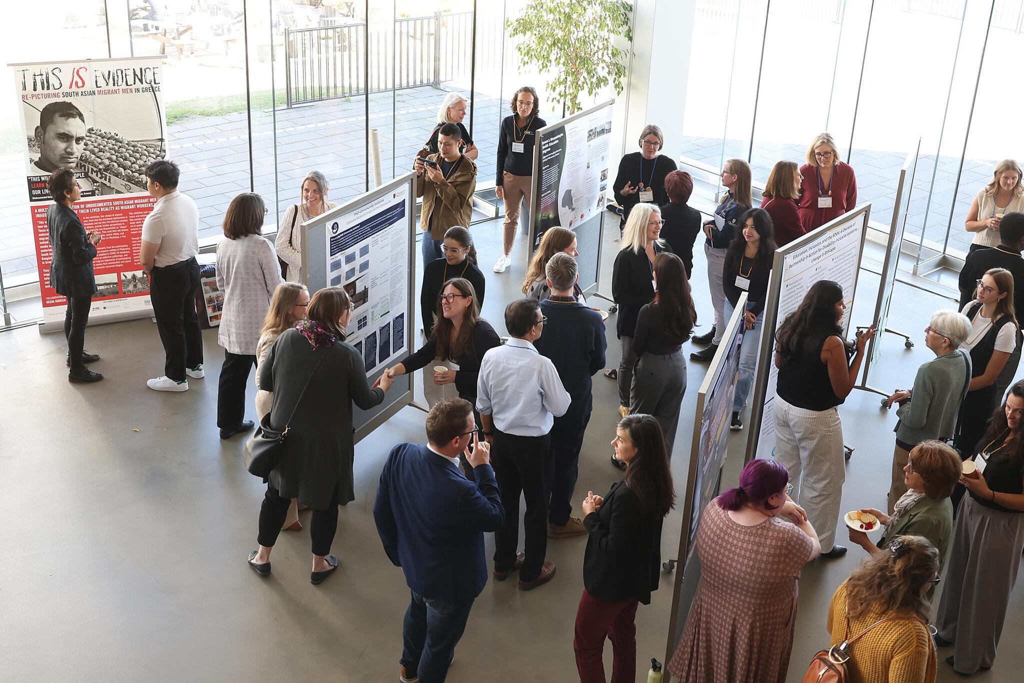 People standing around poster displays viewing and talking