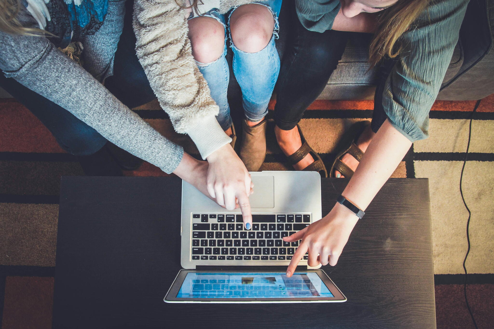 3 people looking at the same laptop screen and pointing