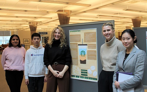Students standing beside poster