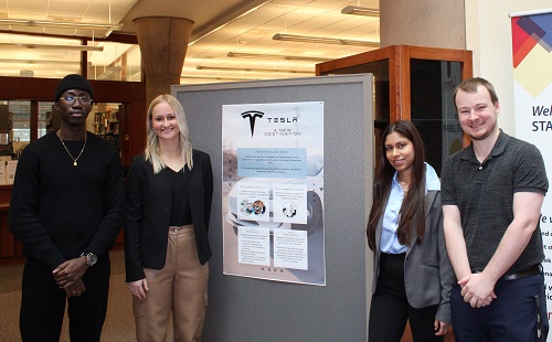 Students standing beside poster