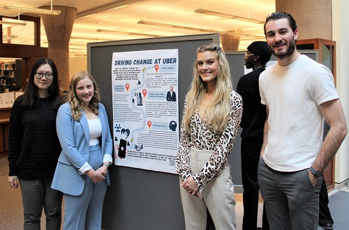 Students standing beside poster
