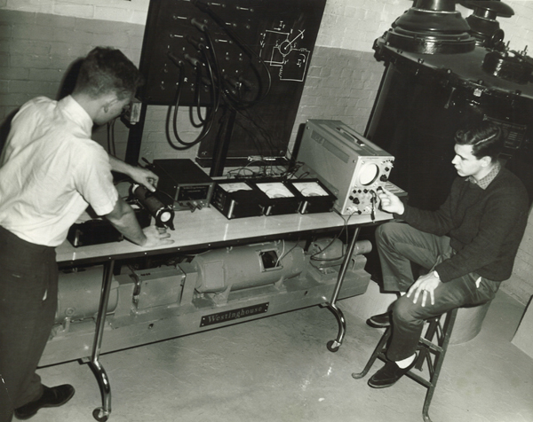 [photo of students studying results on a motor-generator bench in Fleming Hall, 1964]