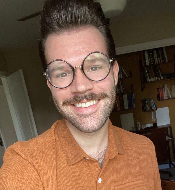 Photo of Jesse smiling in button-down shirt and round black glasses