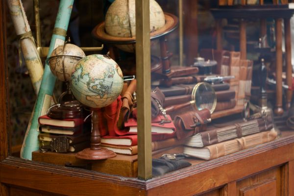 a cabinet full of trinkets like maps and a small world globe