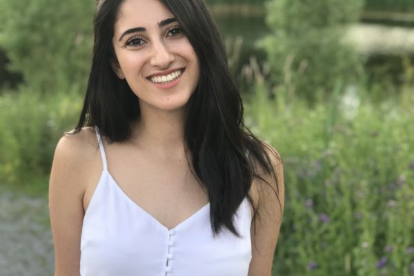 A photo of Nikta in front of a lake and greenery. 