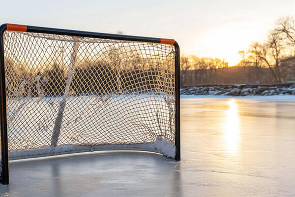 an empty outdoor hockey net on a frozen lake during sunset.