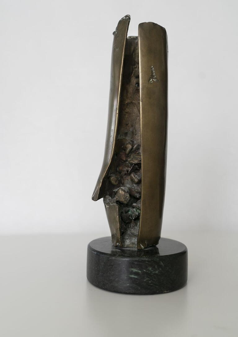 pictured is a bronze sculpture. sculpture is cylinder shape with an opening to the inside of the object  