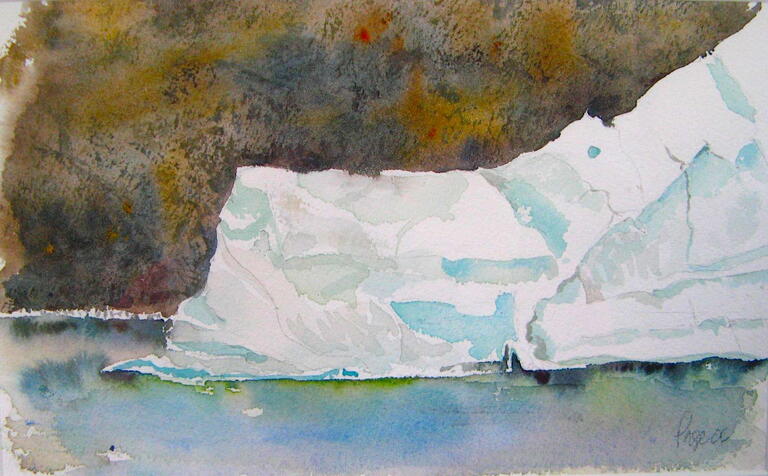 image of iceberg floating in water with shoreline behind it