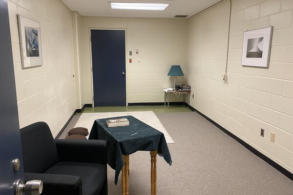 White room with beige floor, blue lounge chair, small side table with a book on it at Duncan McArthur Hall. Go to campus map.
