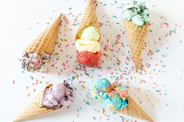 6 ice cream cones with colourful ice cream on a sprinkle covered white table