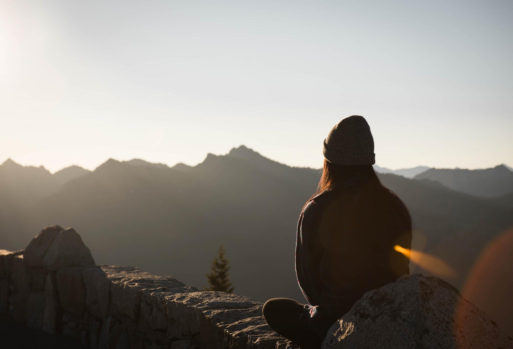 person meditating looking at mountains 