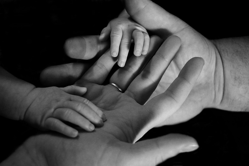 Baby's hands on adults' hands.
