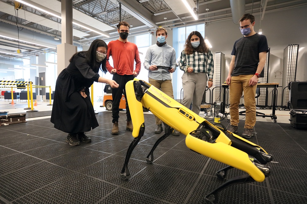Researchers interact with the Spot robot at the Ingenuity Labs.