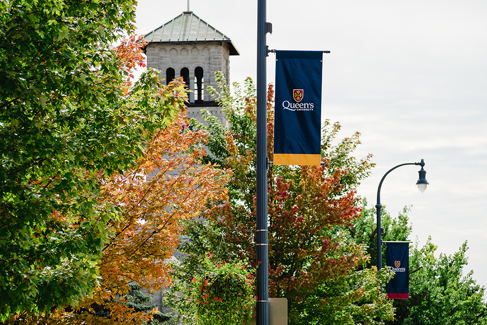 Photograph of Queen's pole pennant in front of Grant Hall.