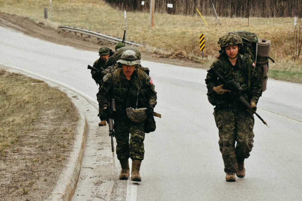 Canadian military members walk along a country road.