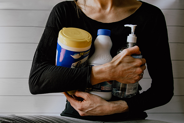 A women holds several cleaning products in her arms