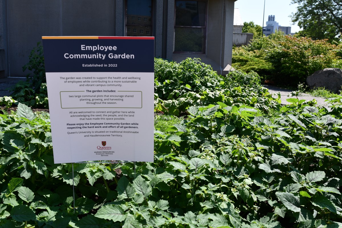 A sign with information in front of the community garden