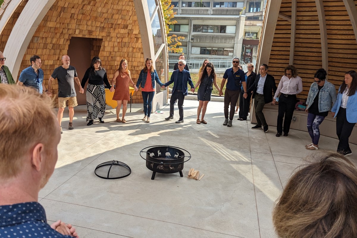 Photograph of attendees taking part in a round dance in the new Indigenous gathering space on Queen's campus during the opening event.