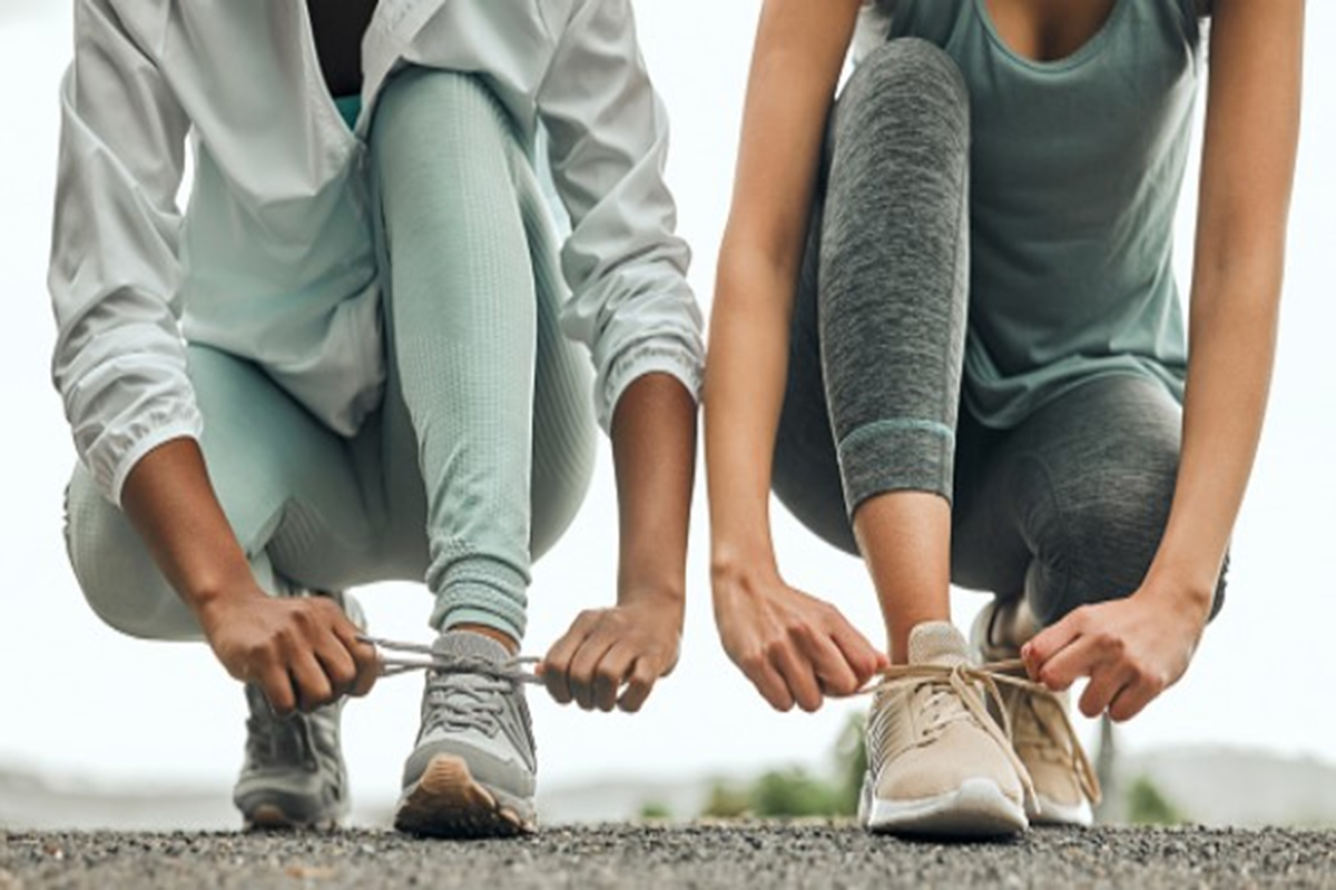 Two women runners tie their shoes.