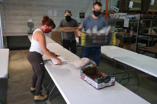 [photo of masked staff in a warehouse packing food]