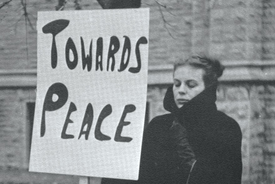 [1964 phoro of a Queen's student holding a sign that says "Towards peace"] 