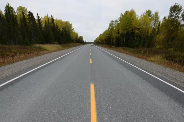 A smooth road cuts through the wilderness of northern Ontario.