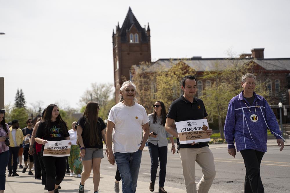 Elder-In-Residence Allen Doxtator, left, Associate Director of the Office of Indigenous Initiatives Aaron St. Pierre, centre, and Provost and Vice-Principal (Academic) Mark Green lead Queen's community members on the advocacy walk in support of the Moose Hide Campaign. (Queen's University)