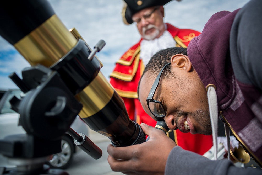 [Photo of a student looking through a telescope]