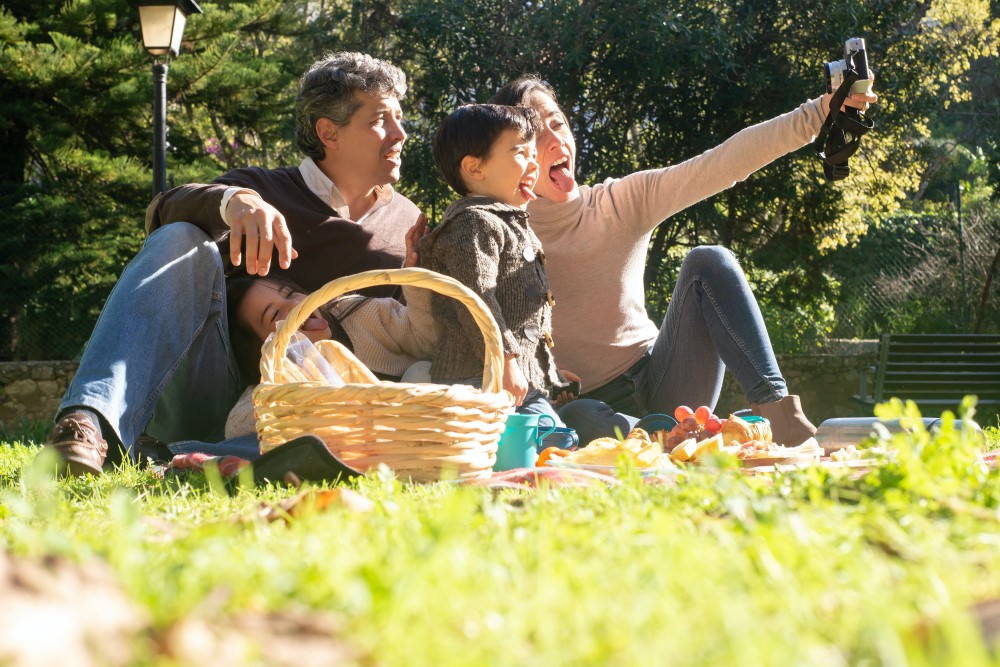 A family takes a selfie during a picnic at a park