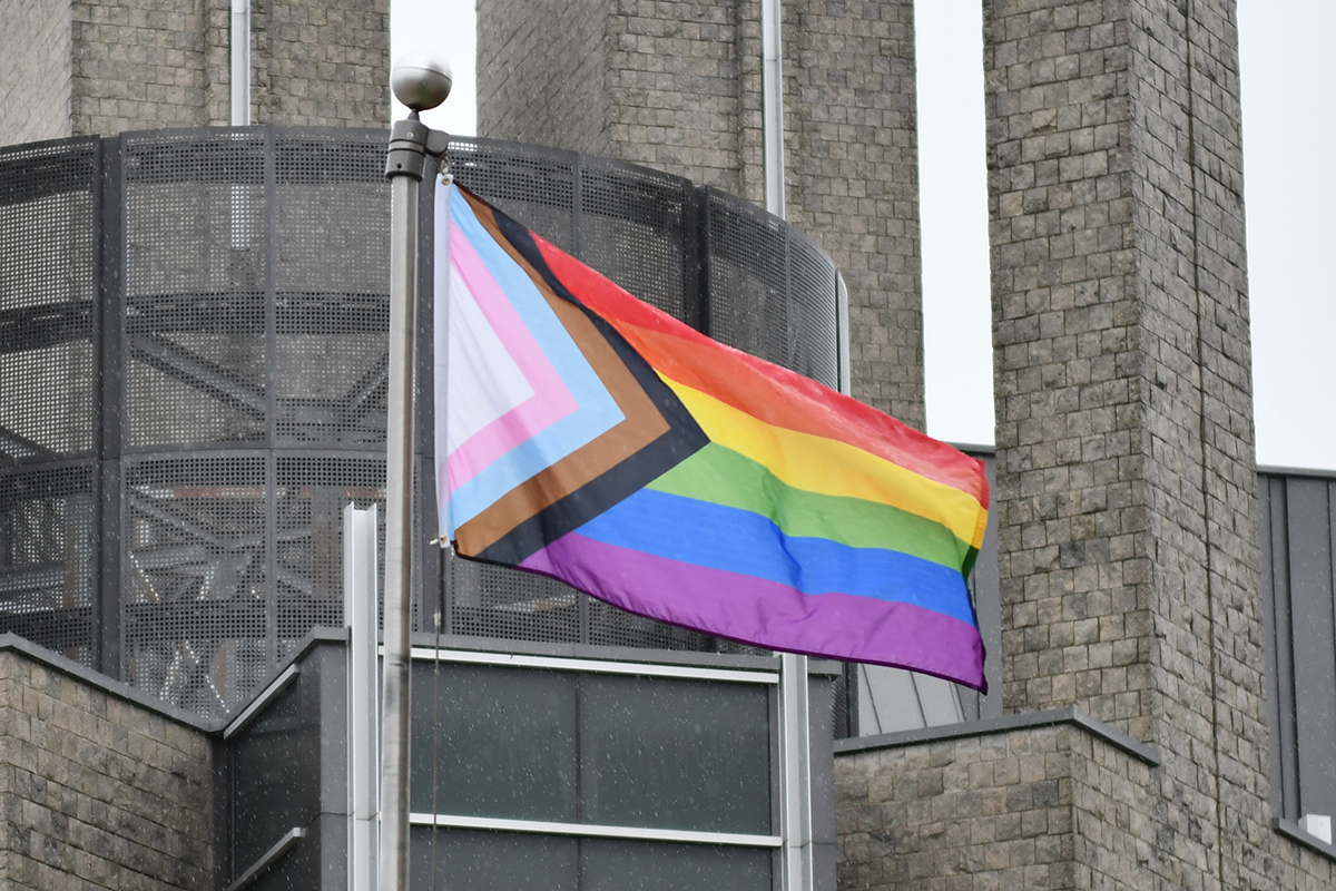 Pride Progress flag flies with Stauffer Library in the background