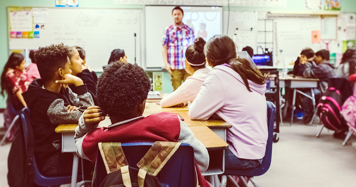 A teacher leads middle school-aged students in a classroom