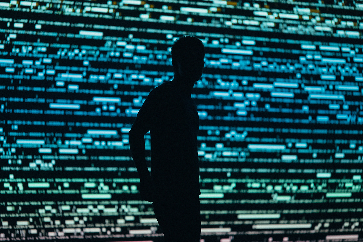 A silhouetted man stands in front of a digital display.