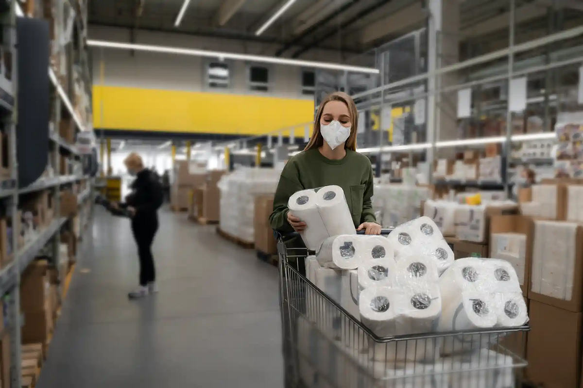 A woman shopper wearing a surgical mask stocks up on toilet paper at a supermarket