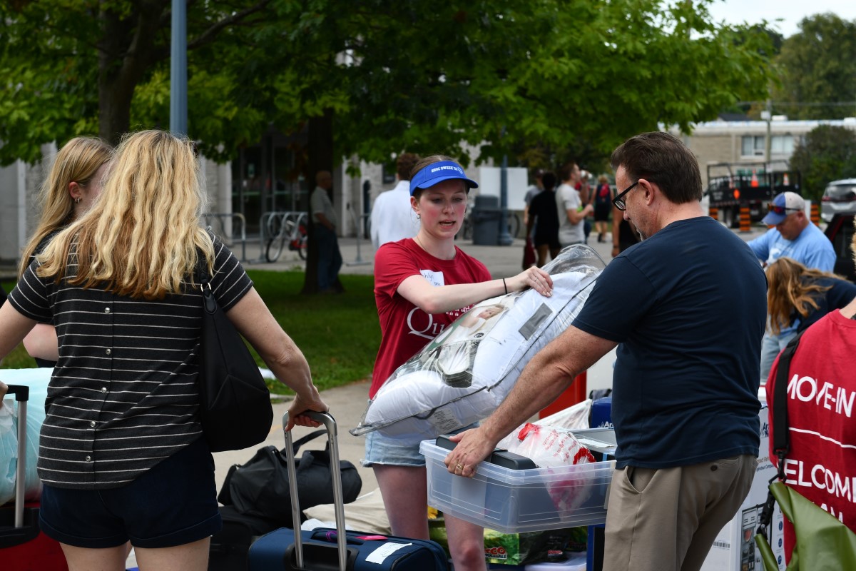 Photograph of Queen's student move-in volunteer assisting a student and their family during Queen's move-in.