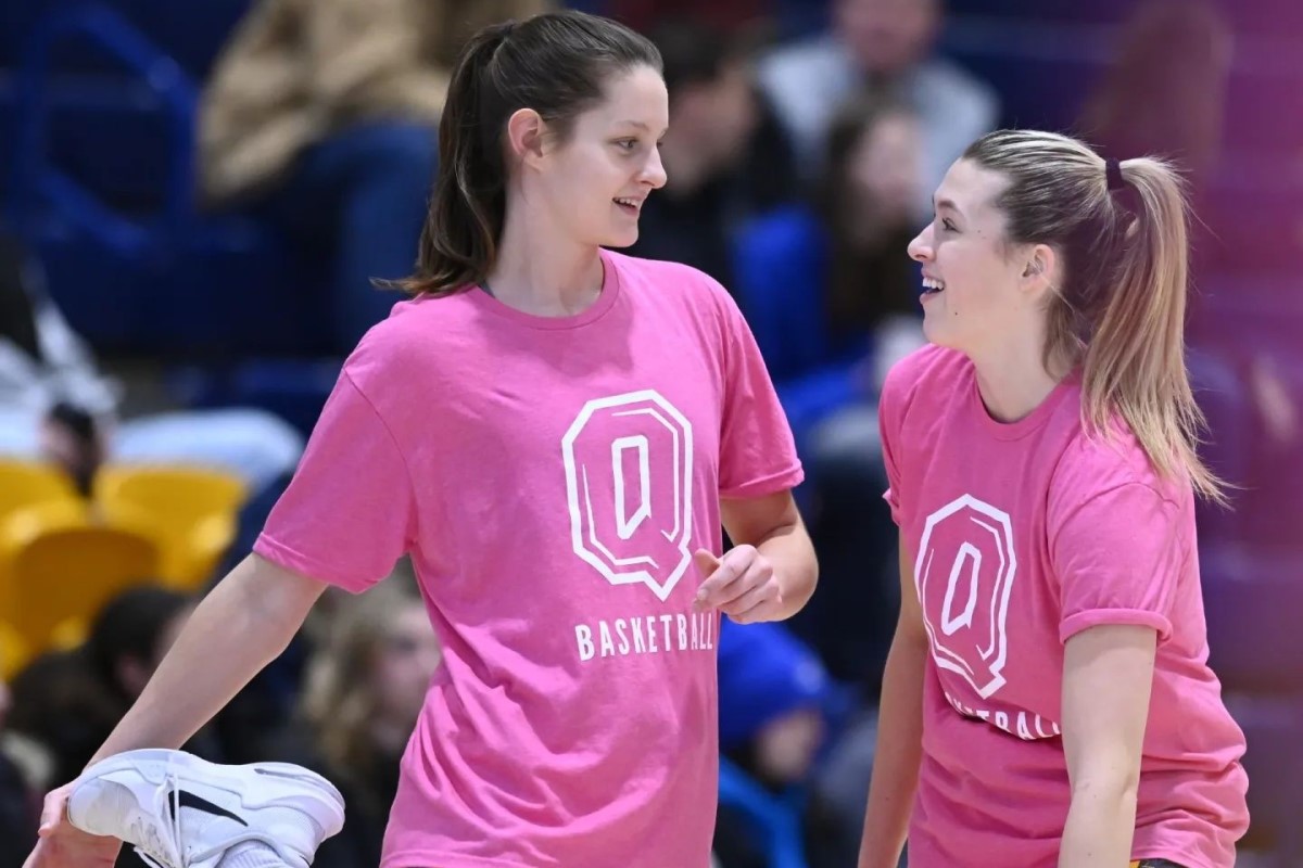 Women's basketball team players wear pink Shoot for the Cure warmup shirts.