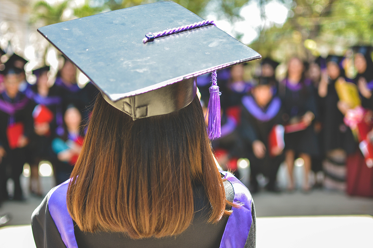 A graduating student takes a group photo of her classmates.