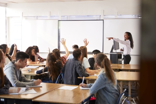 Photograph of a high school teacher calling on students in class.