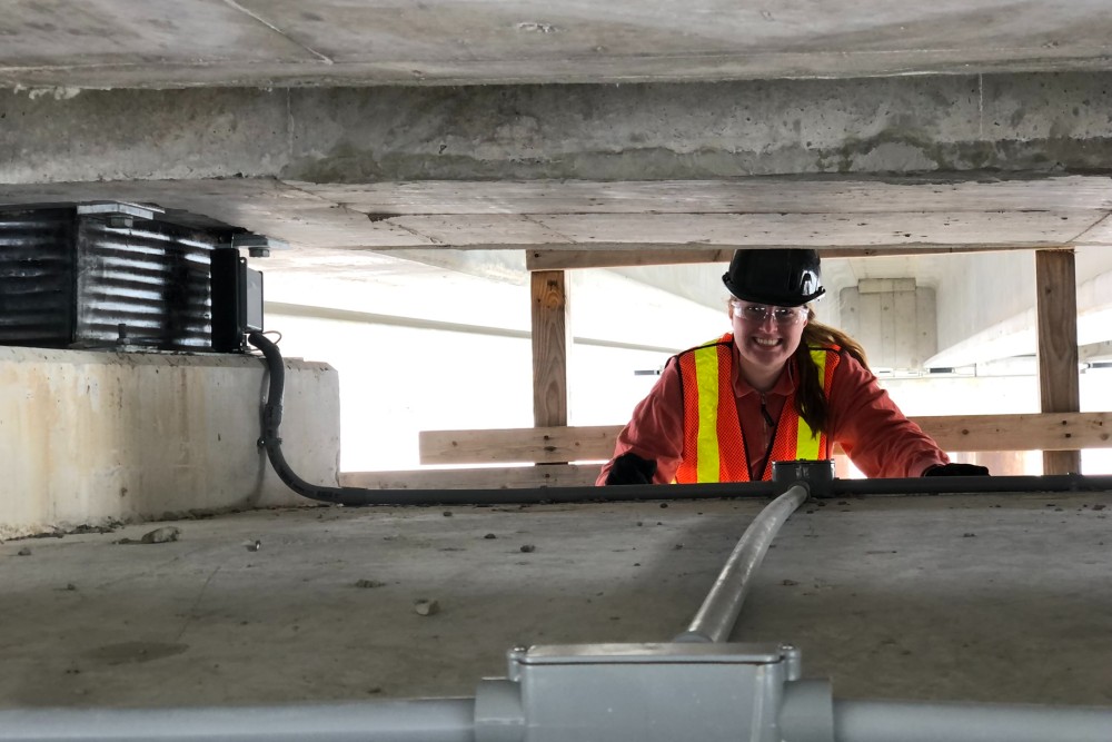 Photograph of Queen's student under the new Waaban Crossing with a newly-installed sensor.