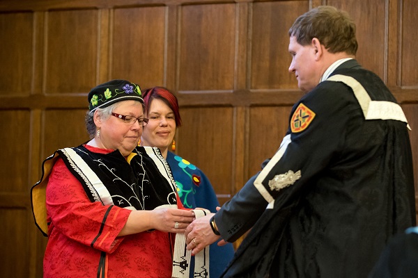 [Principal Daniel Woolf and Kanonhsyonne (Janice Hill) hold a wampum belt]