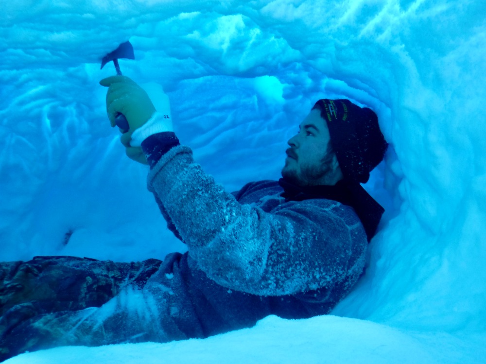 [Photo of a researcher collecting environmental DNA in a maternal polar bear den by Scott Arlidge]