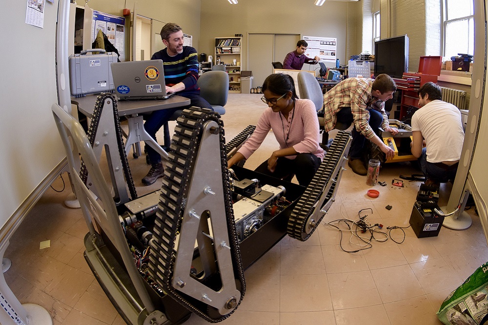 [A group of researchers collaborating in a space with mobile robots]