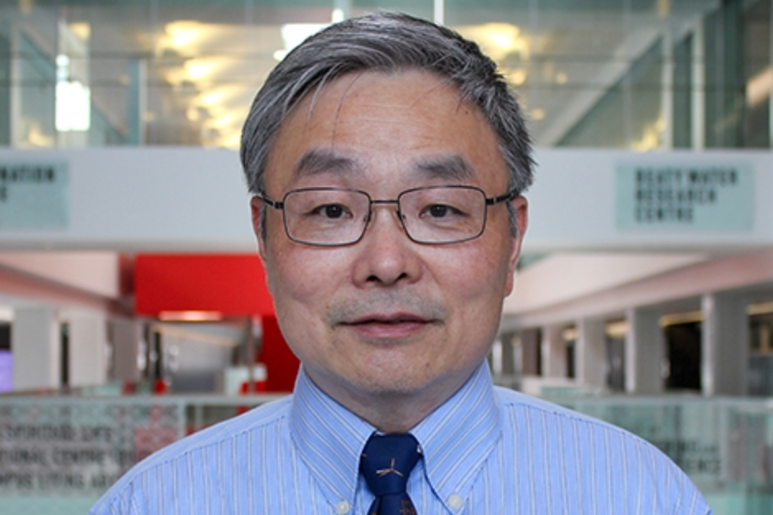 Man with blue shirt and tie standing inside of a building