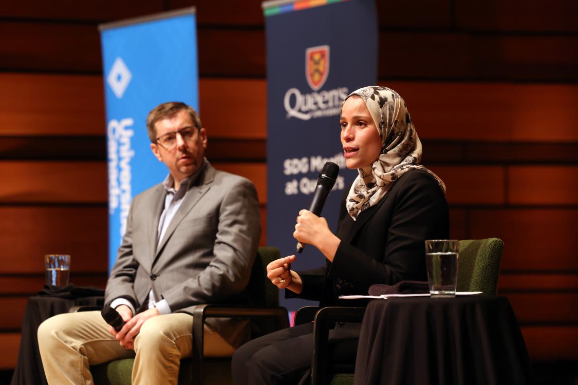 Man and woman holding microphone sitting on a stage 