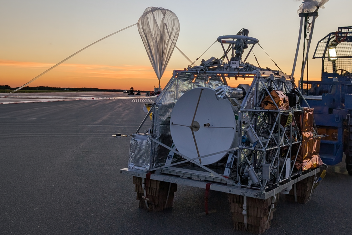 Radio telescope and balloon against an orange sky 