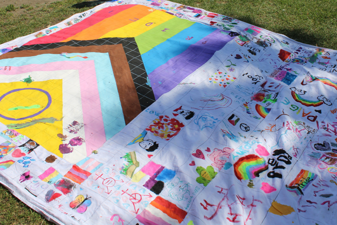 Quilt with pride flag painted on it.