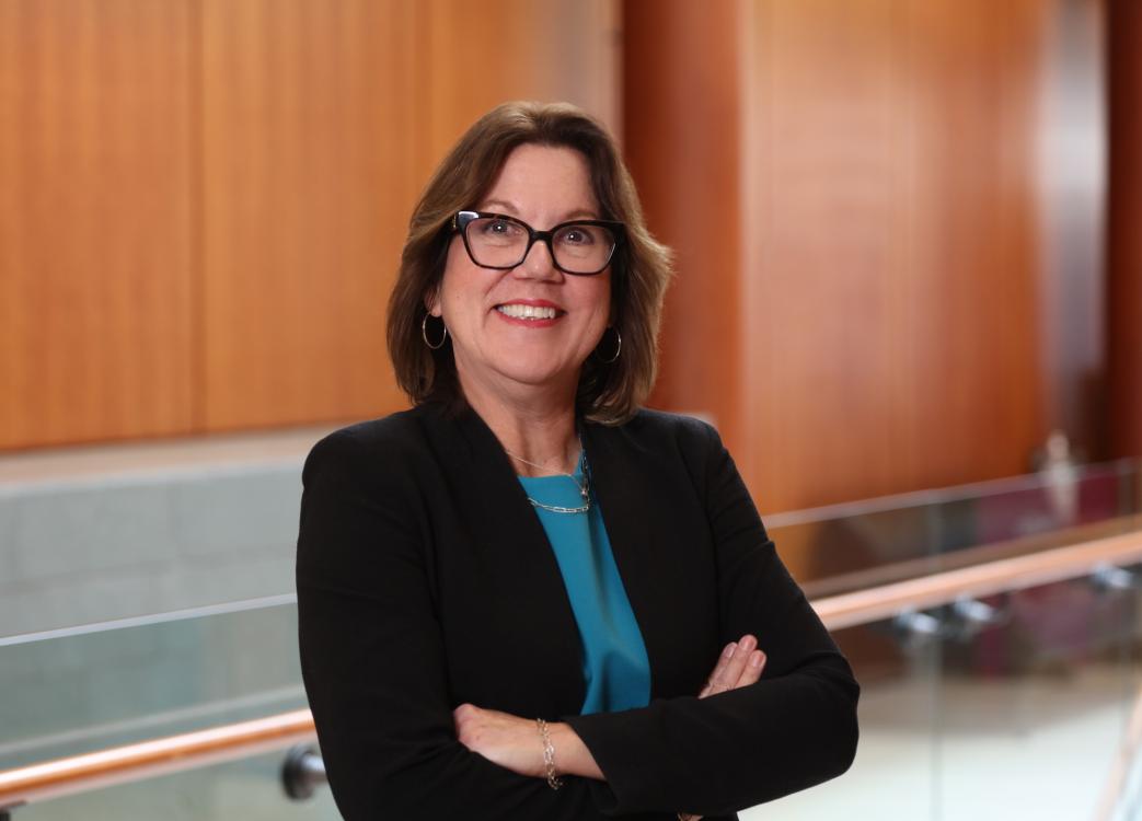 Woman in black blazer and blue shirt smiling